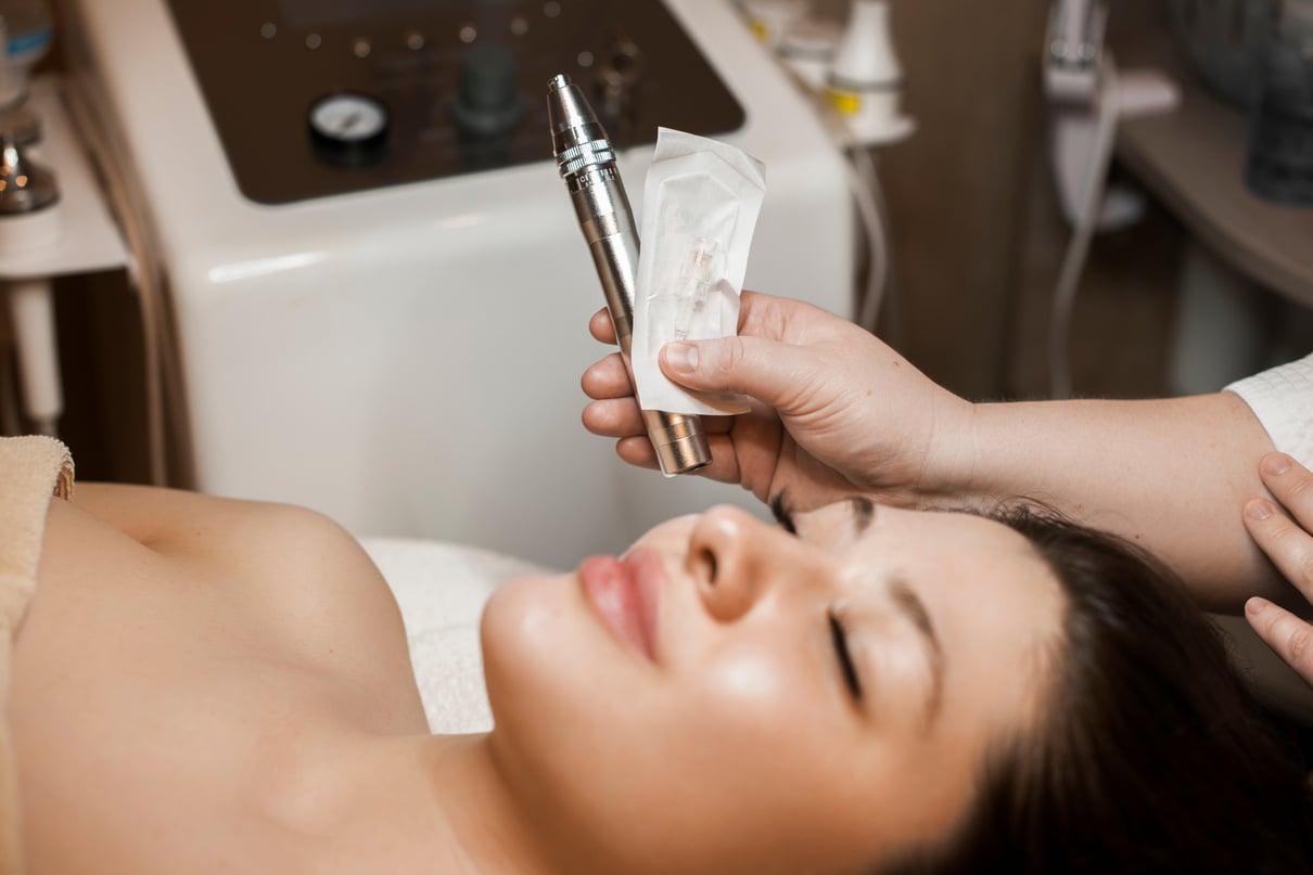 Female cosmetologist hand holding a dermapen for microneedling procedures on the face .